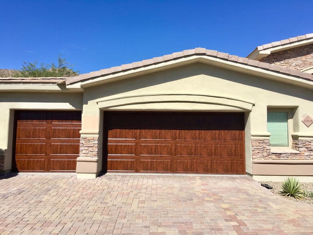 Modern suburban house exterior featuring two wooden garage doors and stone accents.