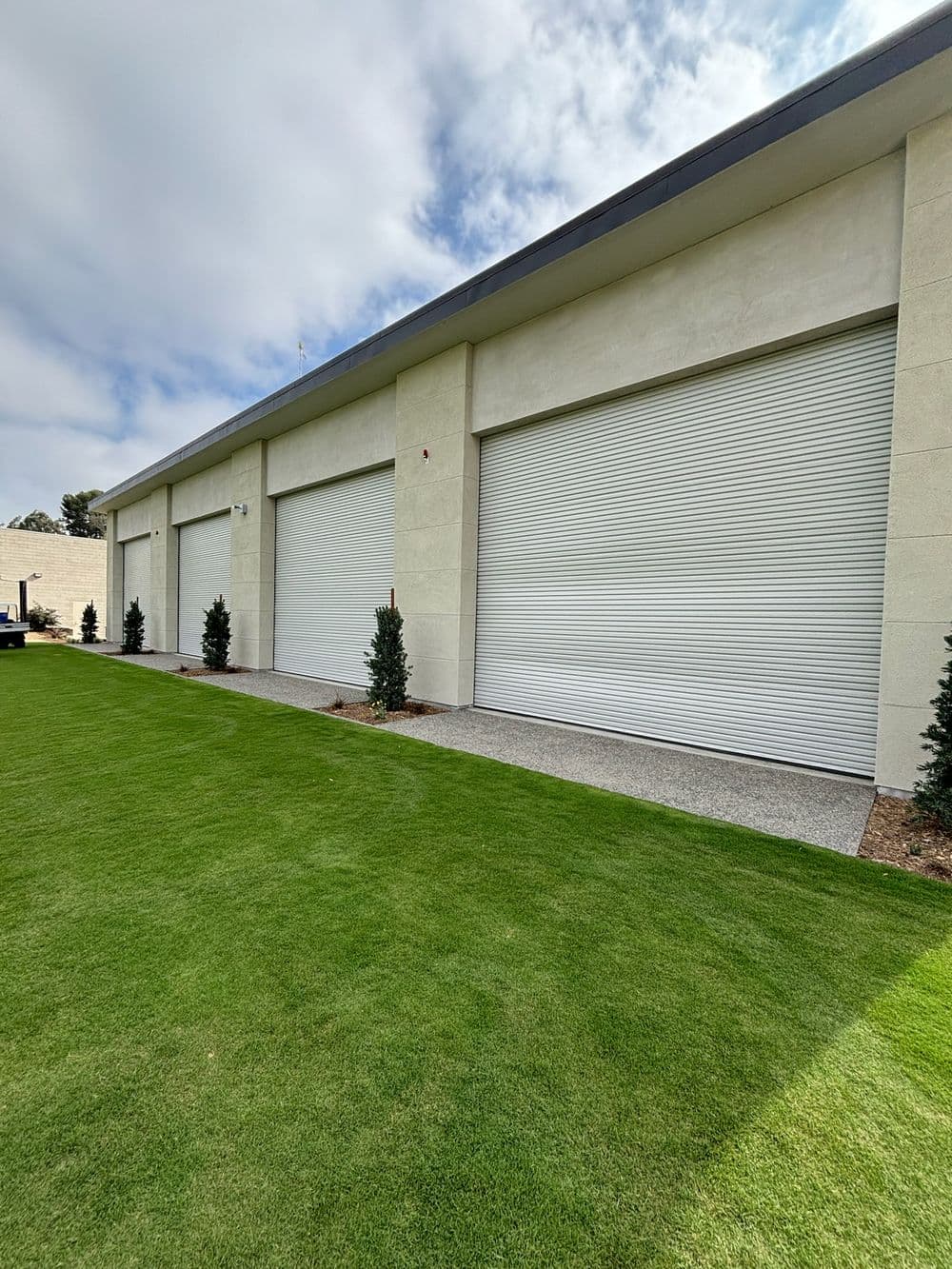 Modern garage storage units with roll-up doors and green grass landscaping.