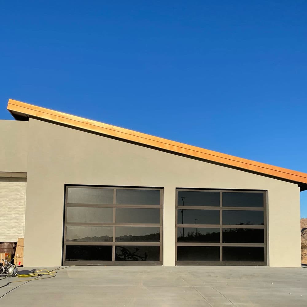 Modern garage with large windows and a wooden roof, set against a clear blue sky.
